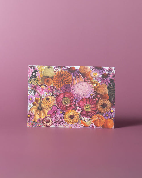 A rectangular box with a dense floral and autumnal print featuring pumpkins, flowers, and leaves in pink, orange, yellow, and purple tones, standing upright on a solid pink background.