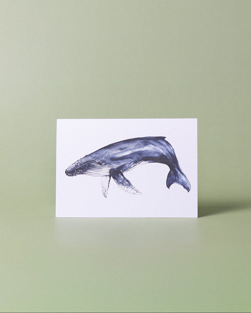A vertical white art print featuring a watercolor illustration of a gray and blue humpback whale, displayed on a light green background.